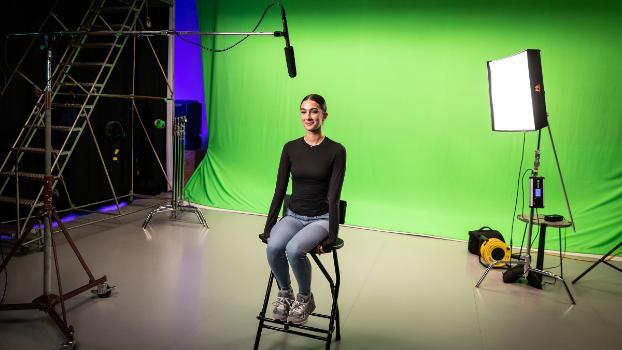 Student in front of green screen for video shoot