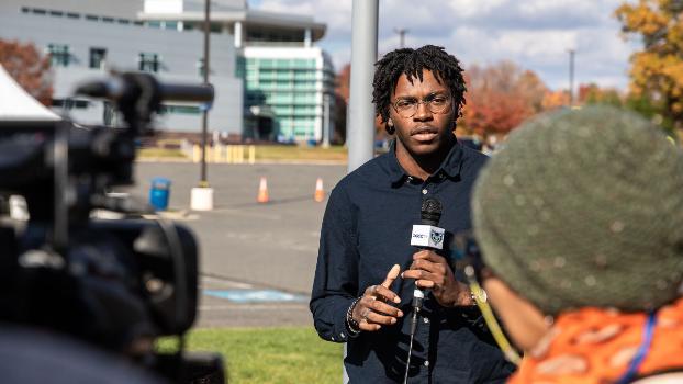 Student in a news coverage video shoot holding a microphone