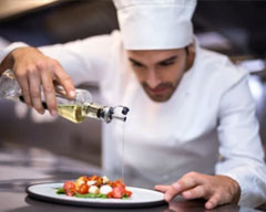 Chef drizzling prepared dish with olive oil